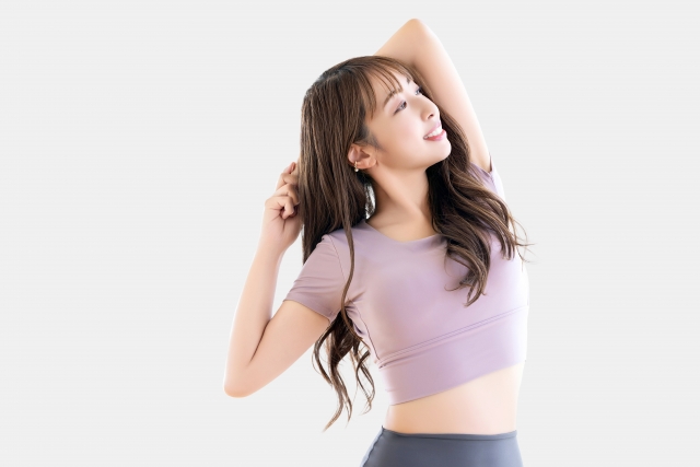 女性が柔軟体操をしている姿, 笑顔で健康的な印象を与える