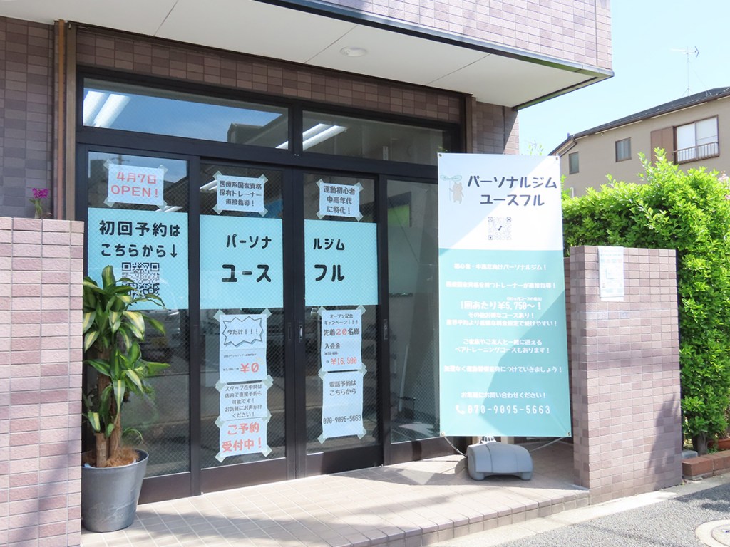 ジムの入り口の写真。ガラスドアには'パーソナルジムユースフル'という看板があり、オープンの案内と初回予約のQRコードが表示されている。